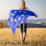 Woman running with waving european union flag in countryside